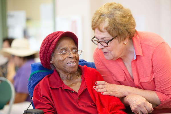 A caregiver interacting warmly with a resident in a facility setting