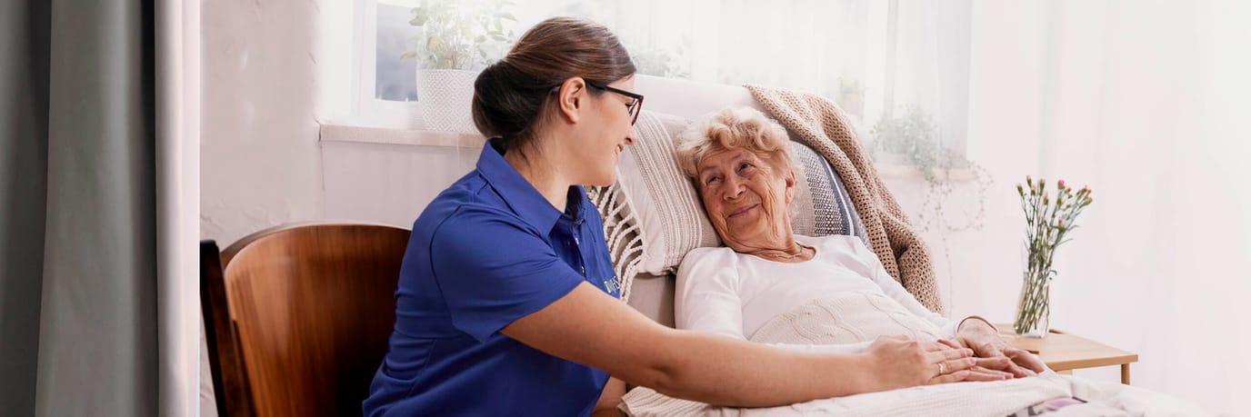 Caregiver interacting with a senior resident in bed.