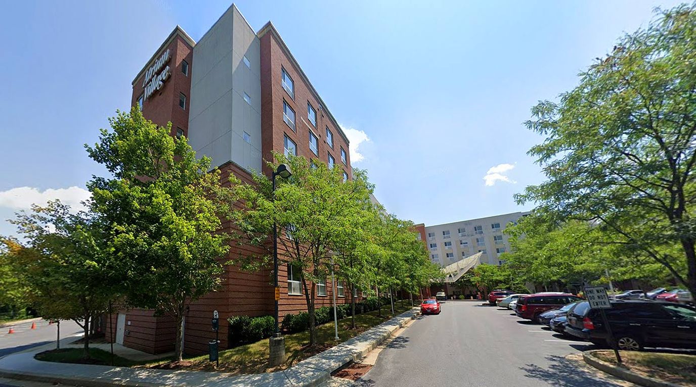 Exterior view of Atrium Village with trees and parking