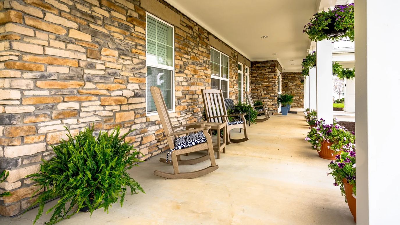 Outdoor porch with rocking chairs and flower pots.