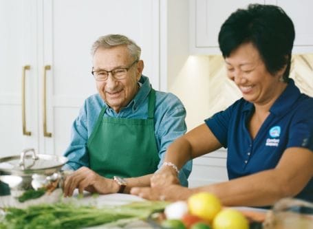 Senior man cooking with staff in the kitchen