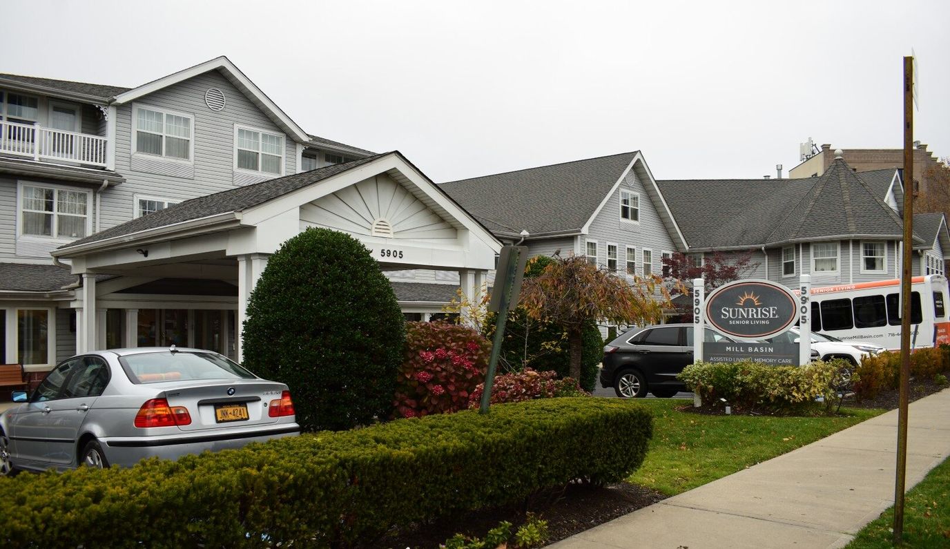 Exterior view of Sunrise at Mill Basin with landscaping and vehicle