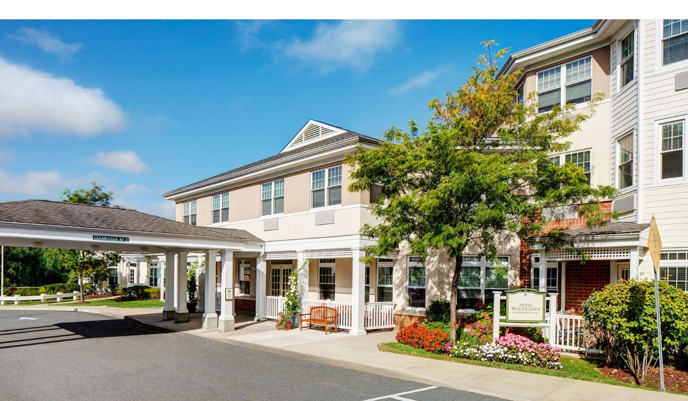 Exterior view of Atria Woodlands with entrance and landscaping