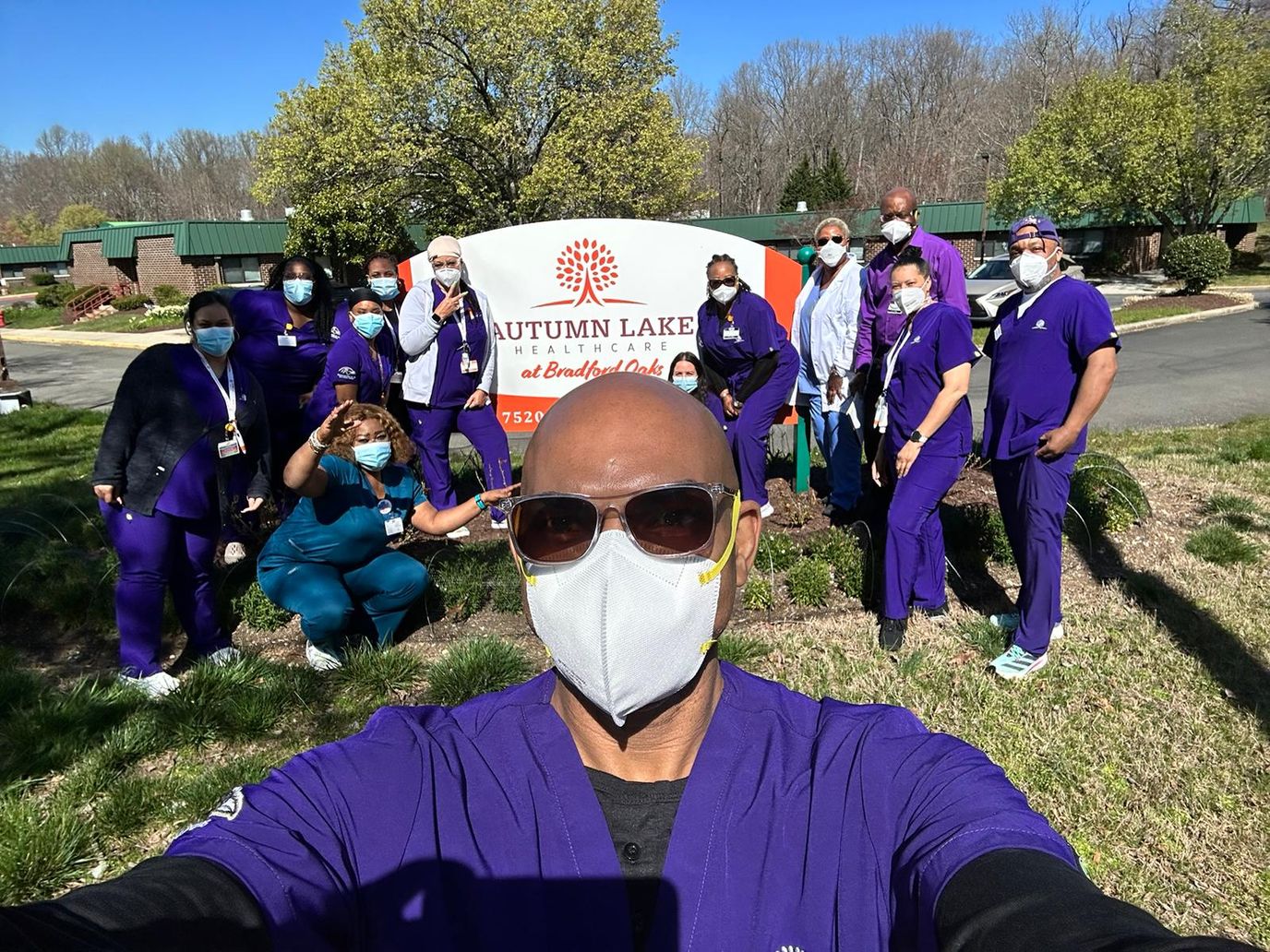 Staff members posing in front of the facility sign