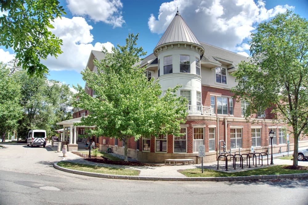 Exterior view of assisted living facility with vehicle and trees