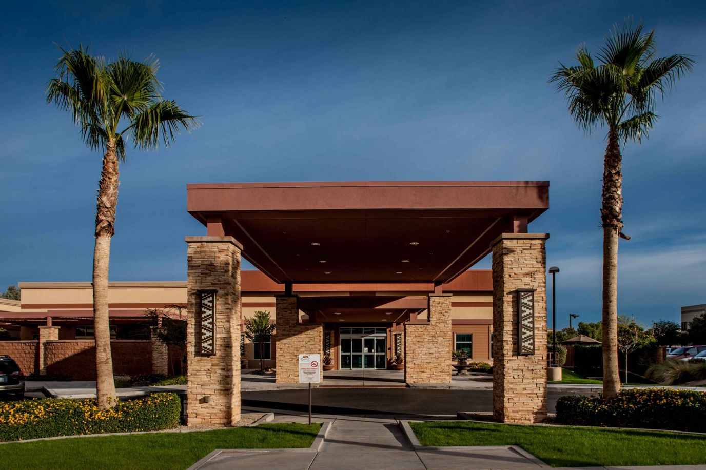 Entrance of a senior living facility with palm trees