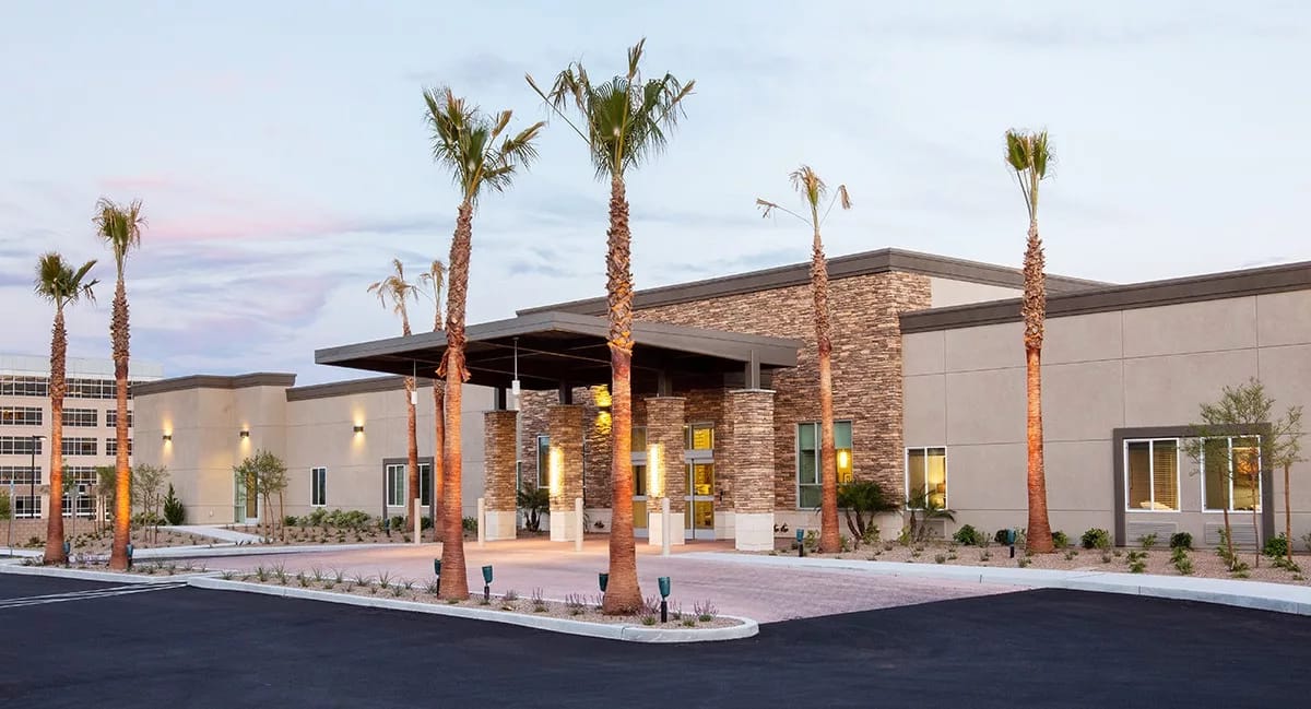 Front entrance of a modern assisted living facility with palm trees