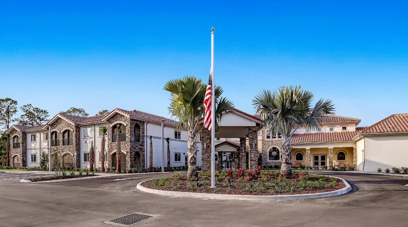 Exterior view of HarborChase facility with gardens and palm trees