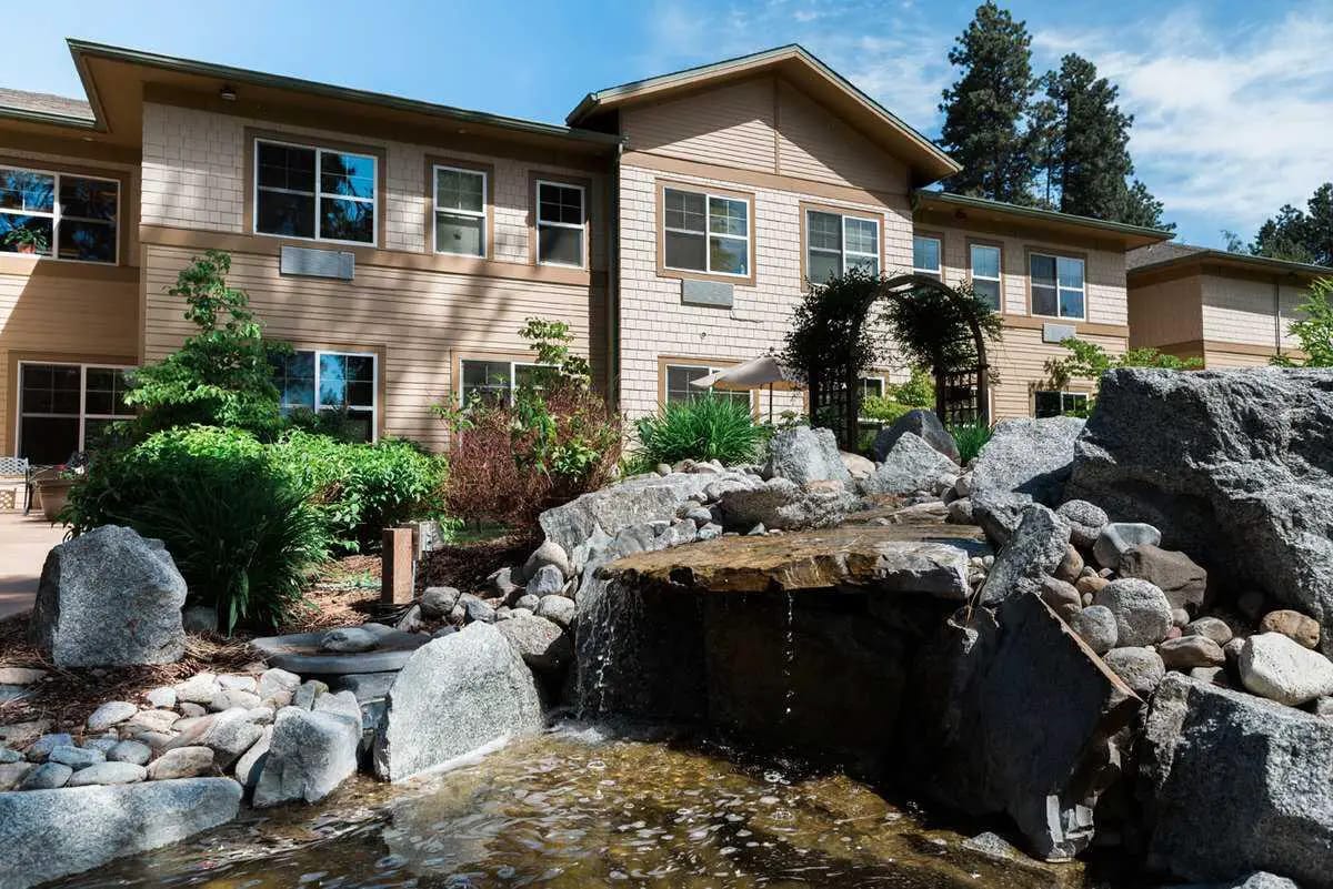 Exterior view of a senior living facility with gardens and water feature