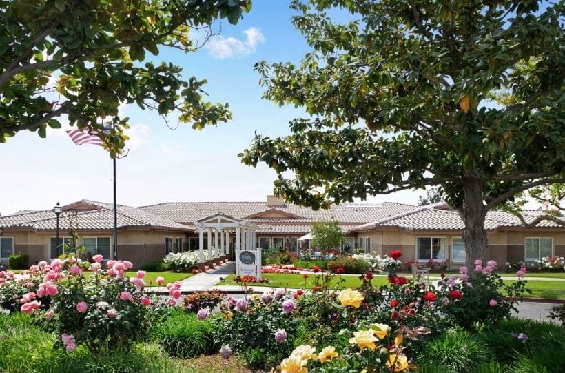 Exterior view of a senior living facility with landscaped flowers
