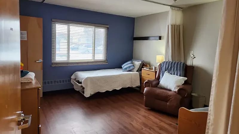 A private resident room with a comfortable chair and bed