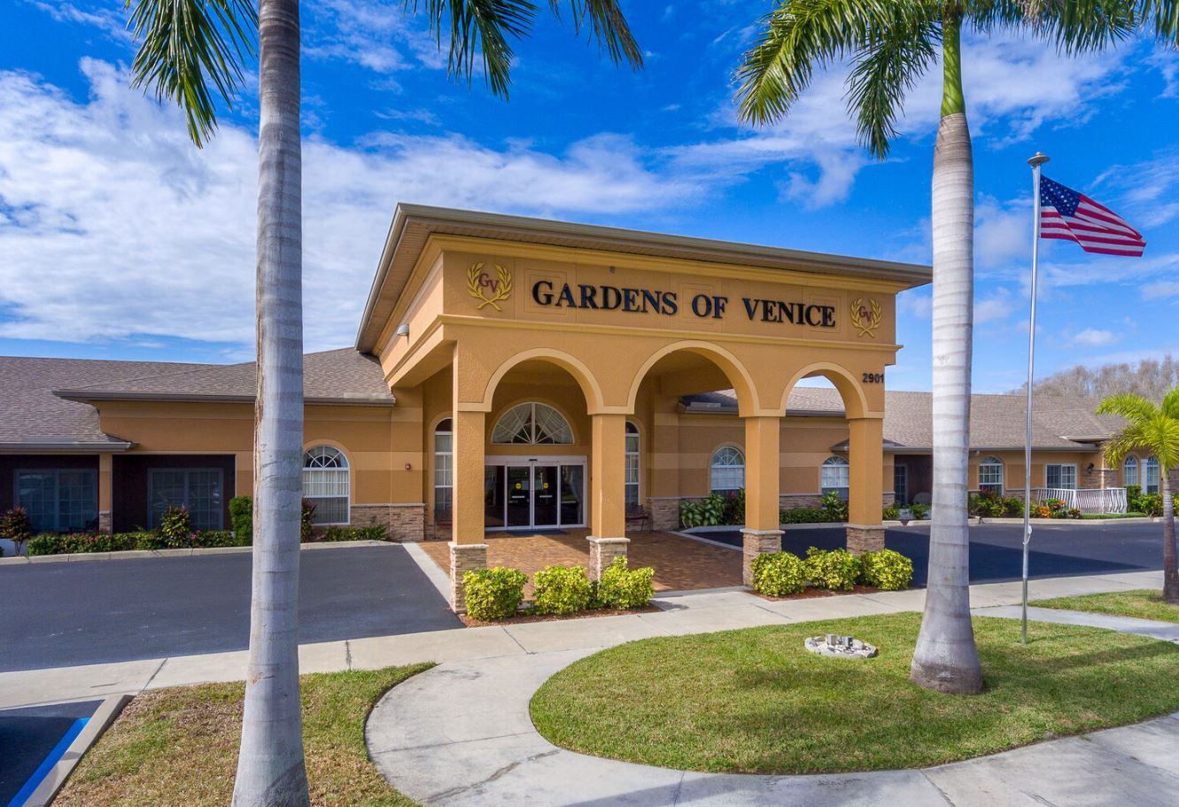 Entrance view of Gardens of Venice facility with palm trees