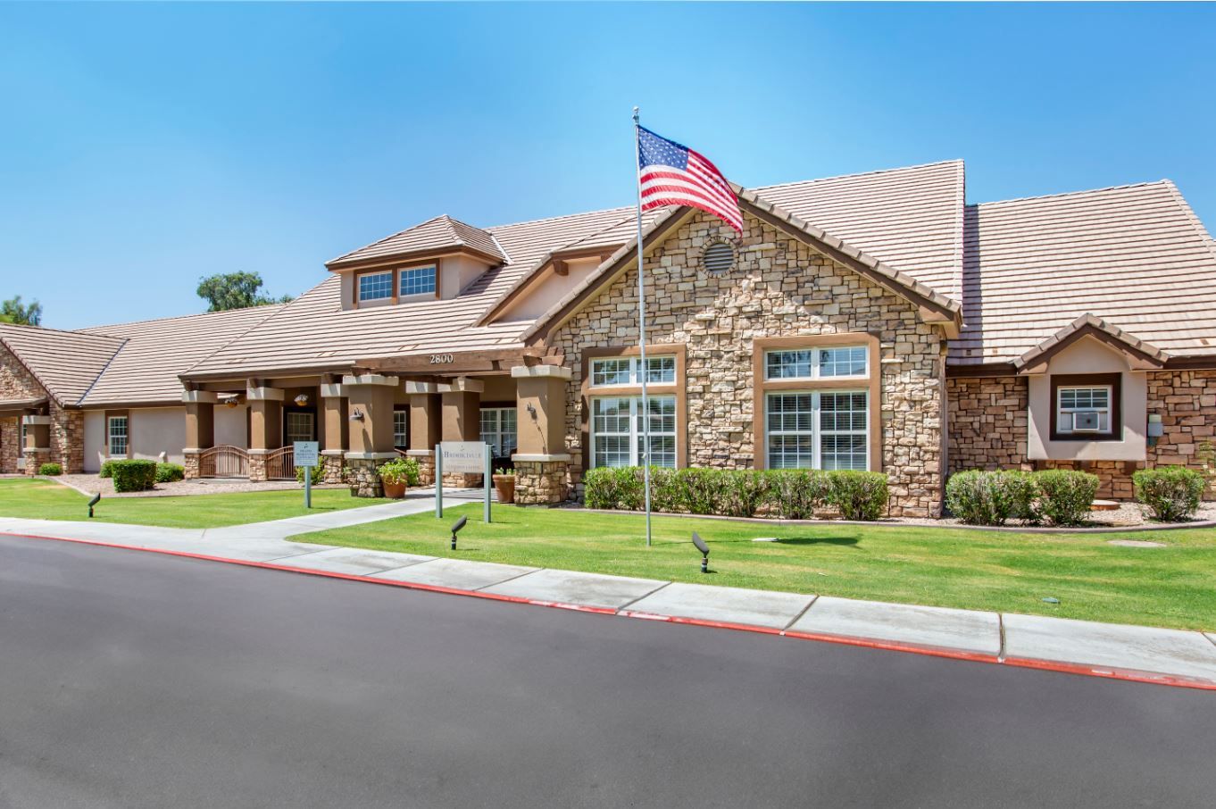 Front exterior of a senior living facility with a flag
