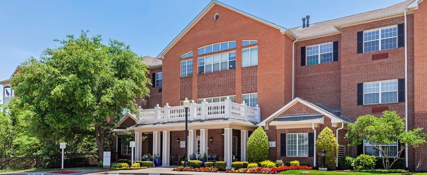 Exterior view of a senior living facility with colorful landscaping
