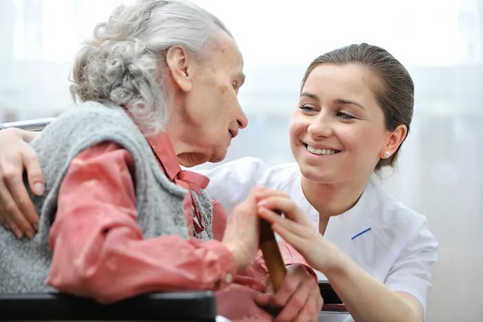 Caregiver smiling and interacting with elderly resident