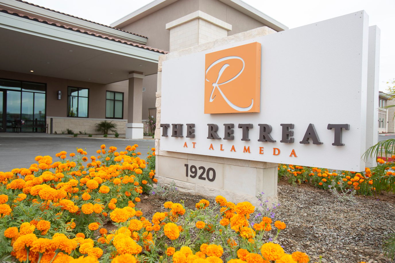 Sign of The Retreat at Alameda with flowers in front