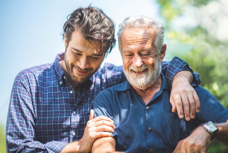Two smiling men enjoying each other's company outdoors.