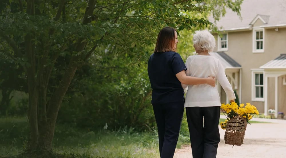 Staff member assisting a resident outdoors with flowers