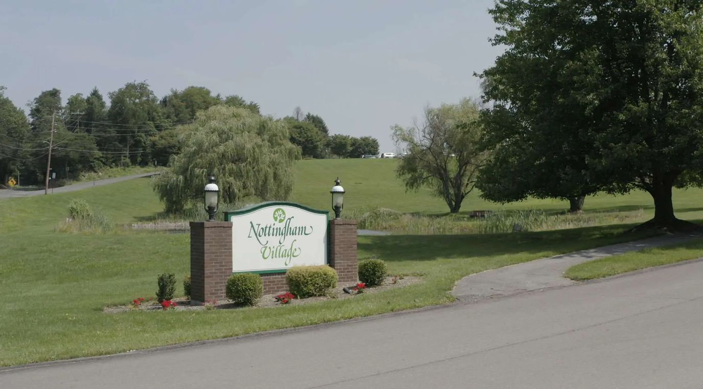 Signage for Nottingham Village near a green landscape