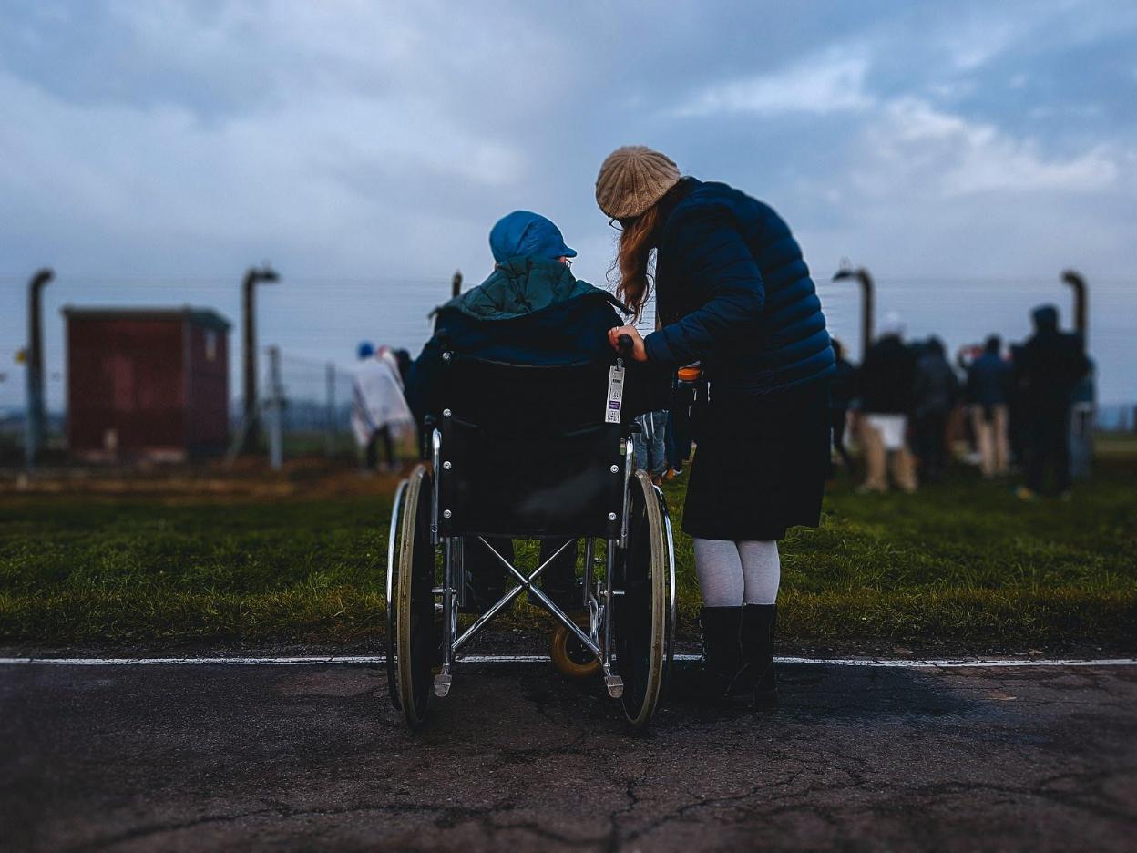 Woman assisting a resident in a wheelchair outdoors.
