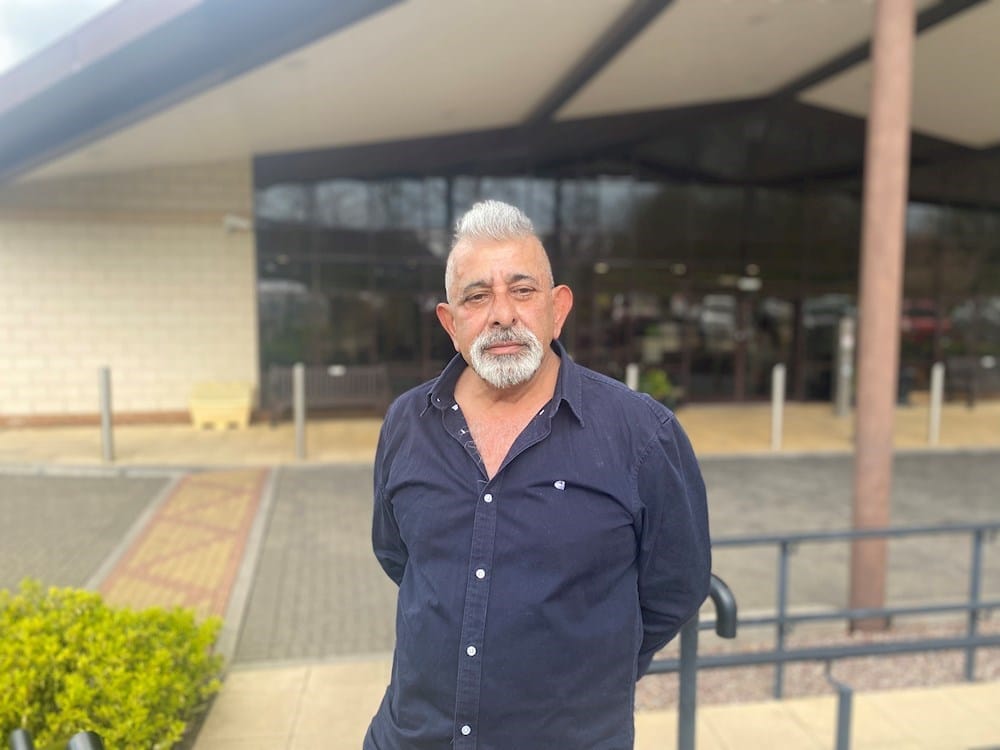 Man standing outside a facility entrance.
