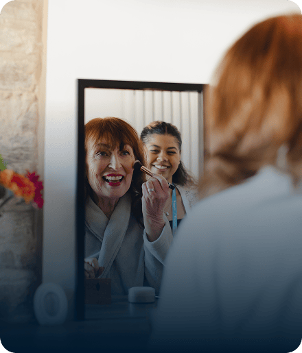 Resident receiving makeup application from caregiver.