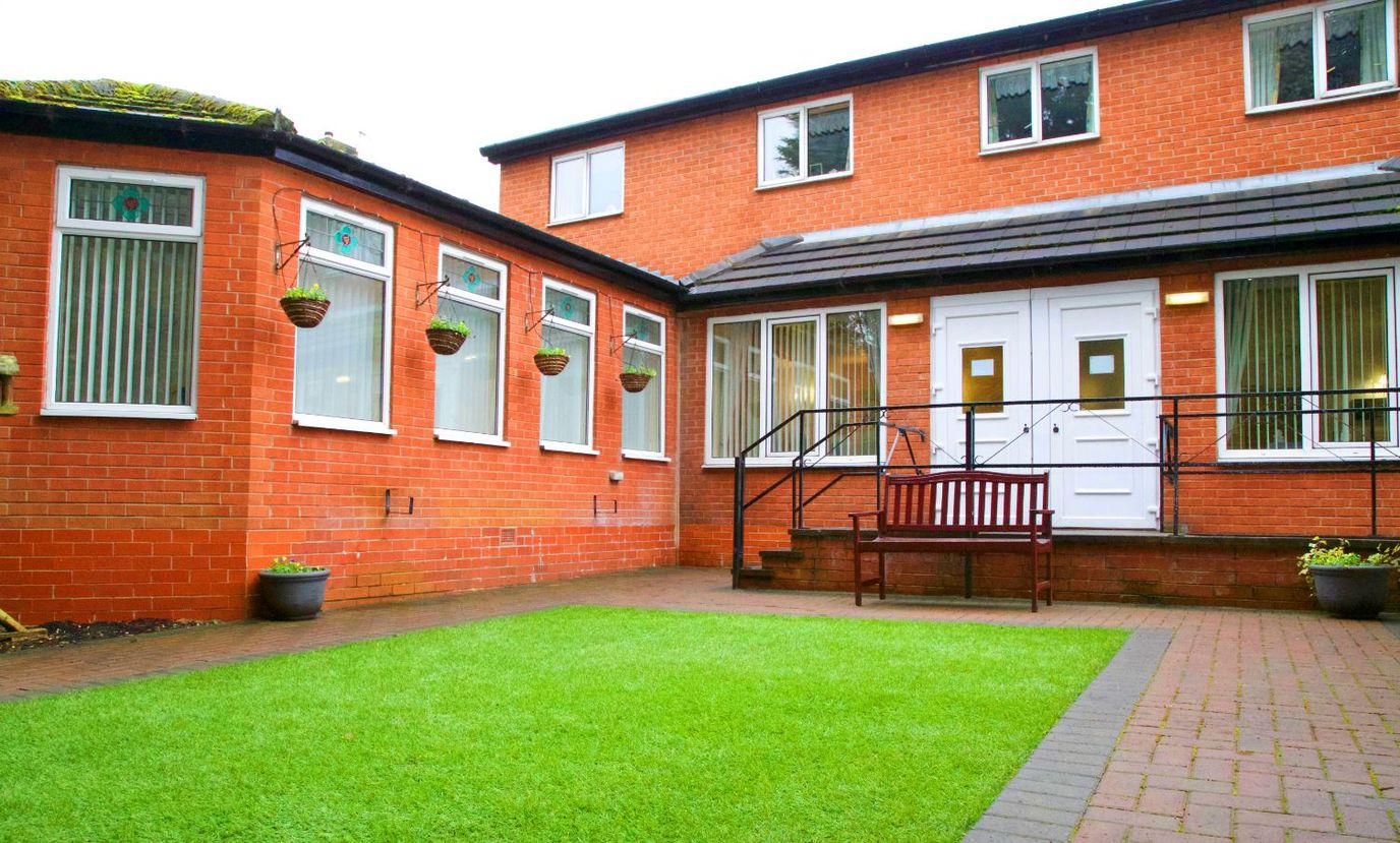 Exterior view of a red brick building with garden