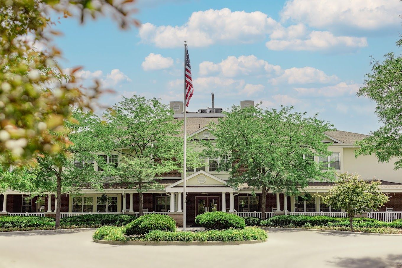 Exterior view of Carriage Court Senior Living with trees and flag