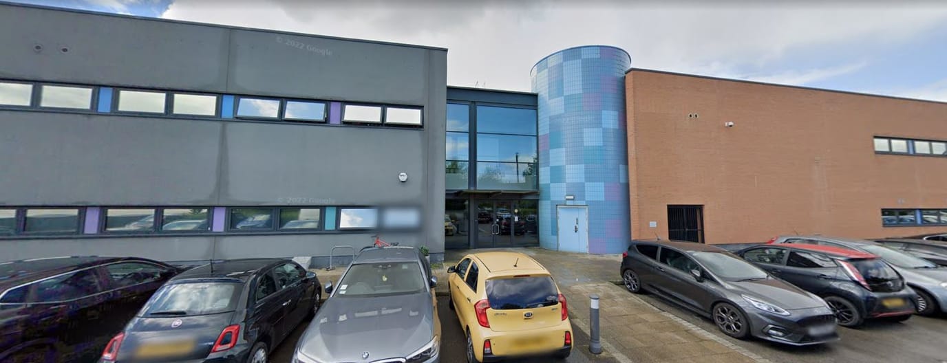 Front entrance of a modern building with cars parked