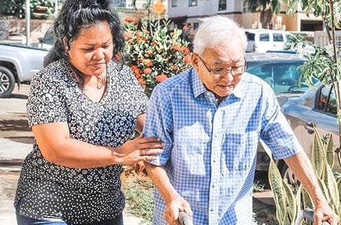 Caregiver assisting an elderly man outdoors