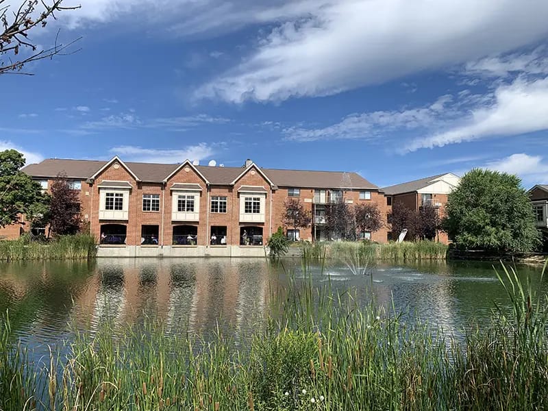 Exterior view of building by a pond with greenery