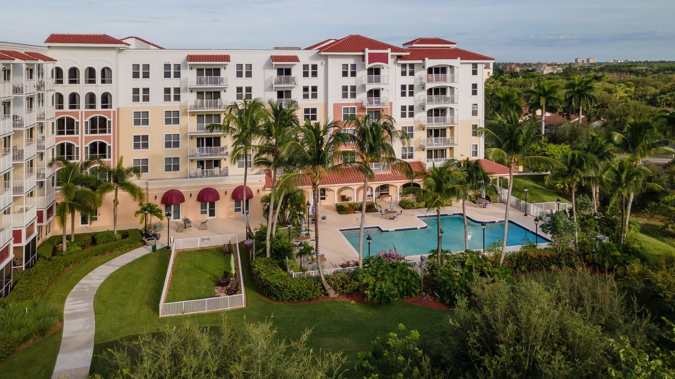 Exterior view of a senior living facility with pool and gardens