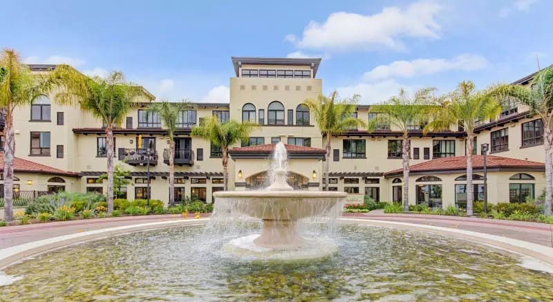 Exterior view of a senior living facility with a fountain