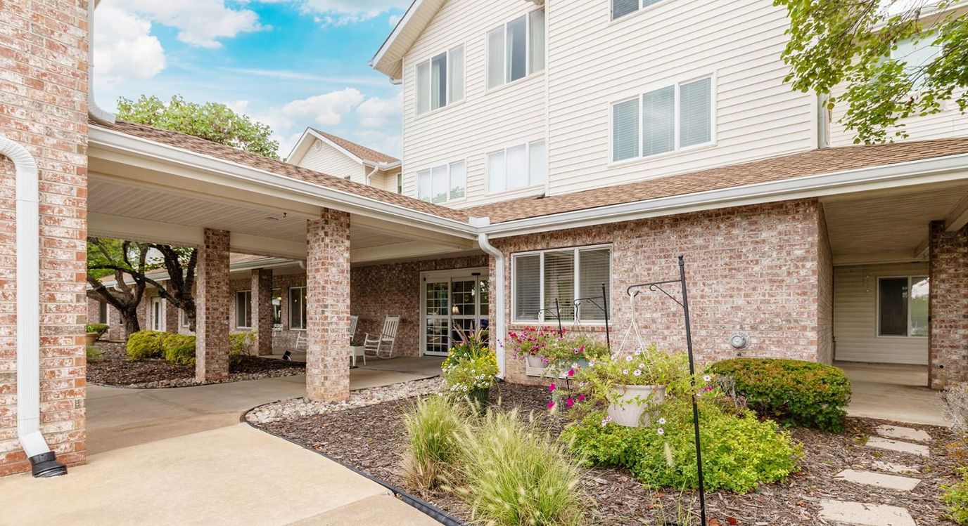 Exterior view of a senior living facility entrance with flowers