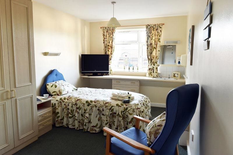 Cozy private room with bed, chair, and TV