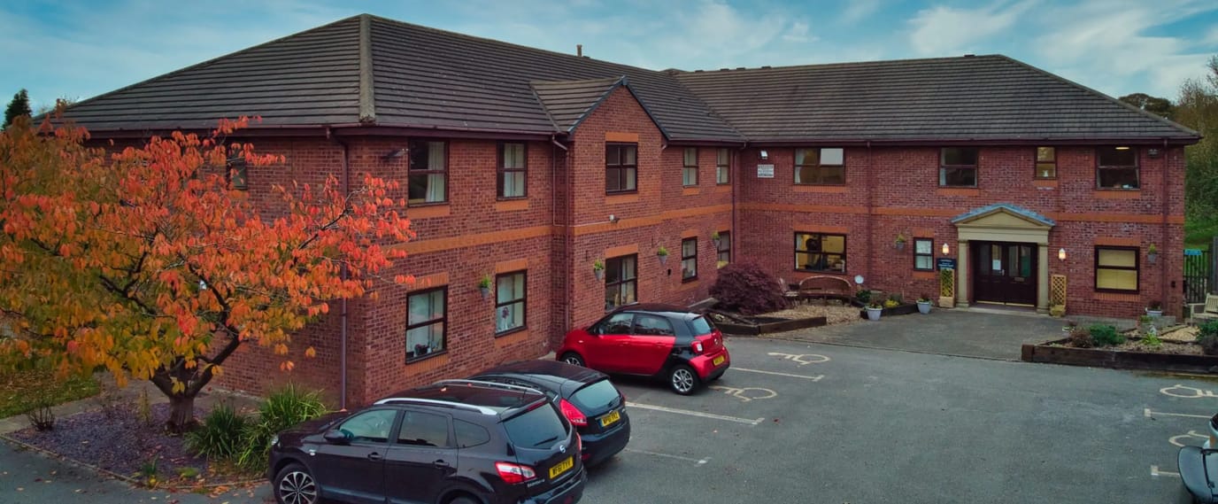 Exterior view of Clement Court Care Home with vehicles