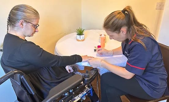 Staff providing manicure service to a resident