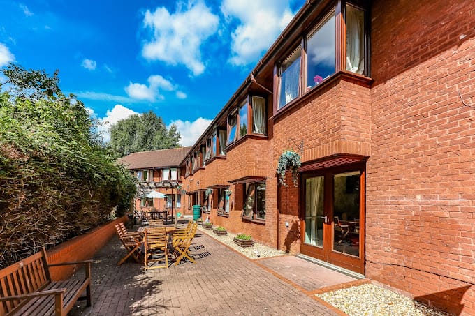 Exterior view of Neath House Care Home with outdoor seating