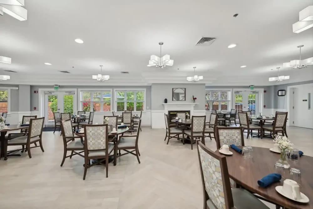 Well-lit dining room with tables set for residents
