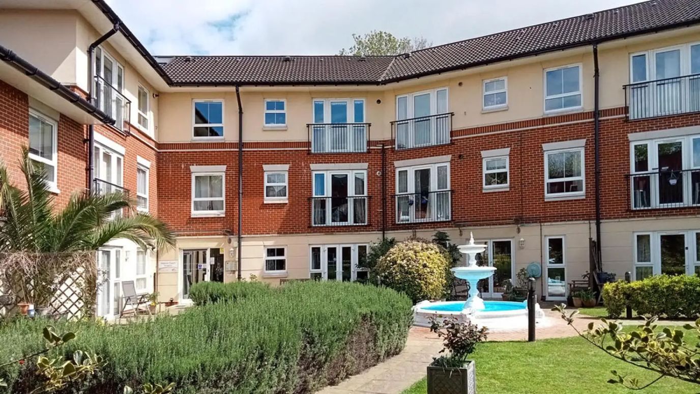 Exterior view of a senior living building with garden