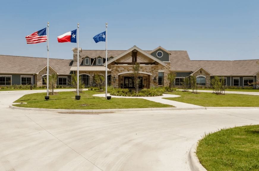 Exterior view of Heritage Place Assisted Living facility with flags
