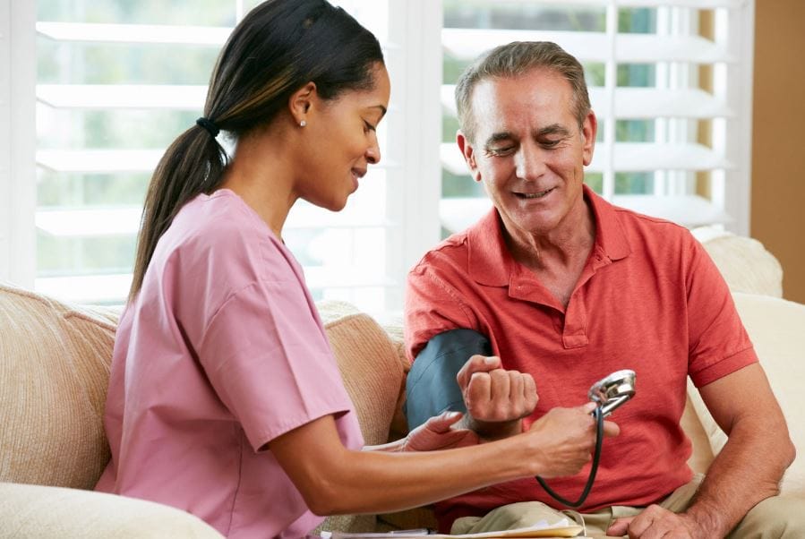 Nurse taking a senior's blood pressure in a cozy setting.