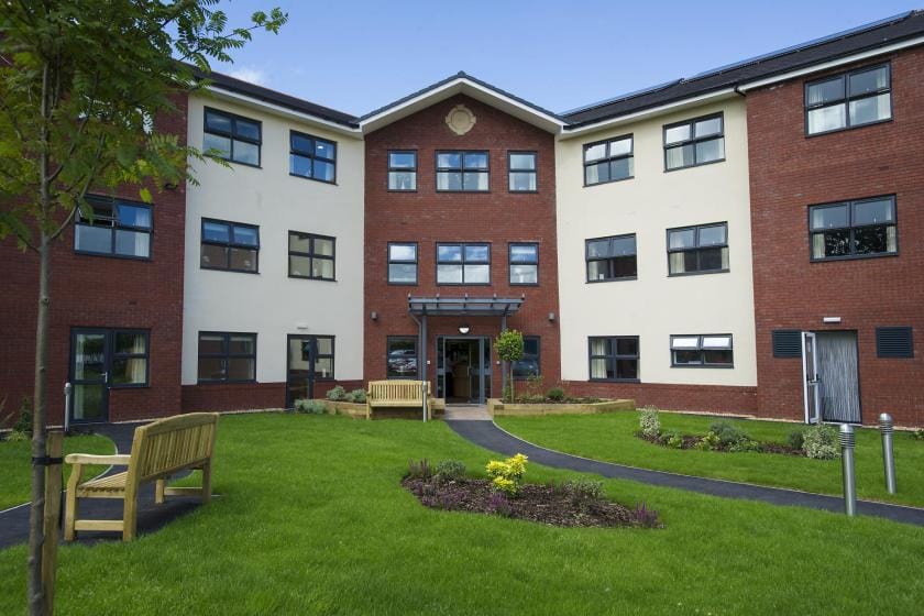 Exterior view of a residential care home with green space