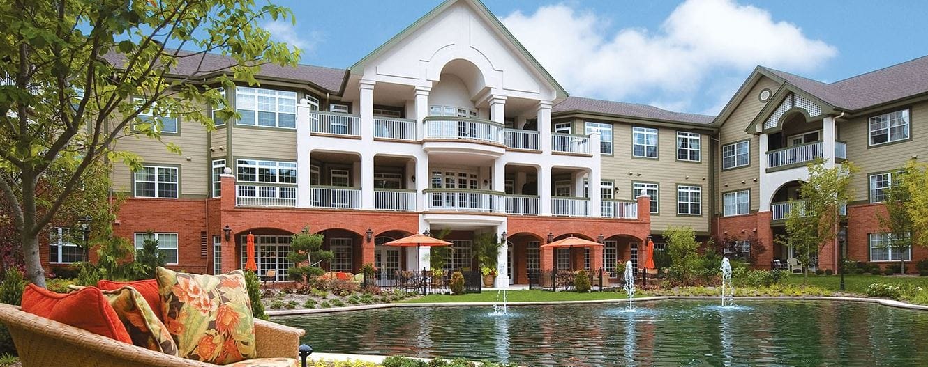 Exterior view of The Gatesworth with a pond and landscaping