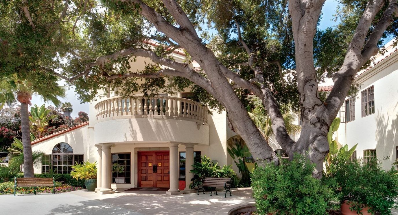 The exterior entrance of a senior living facility surrounded by greenery