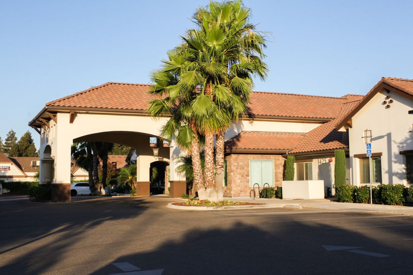 Exterior view of Cedarbrook Memory Care Community with palm trees