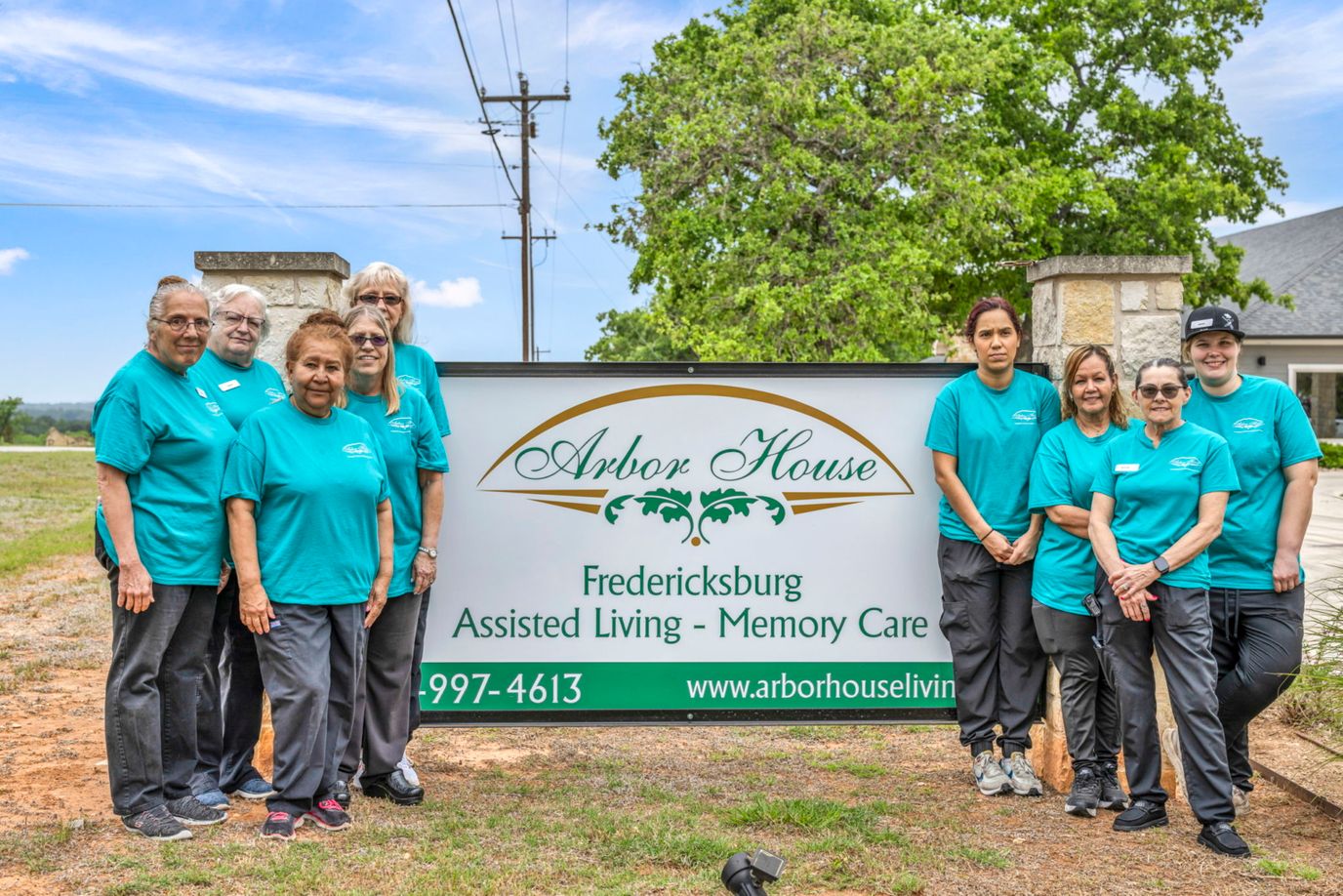 Staff members posing outside the facility sign