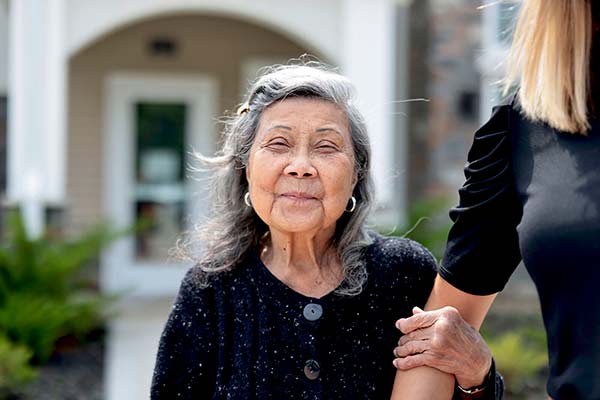 An elderly woman smiling outside the facility