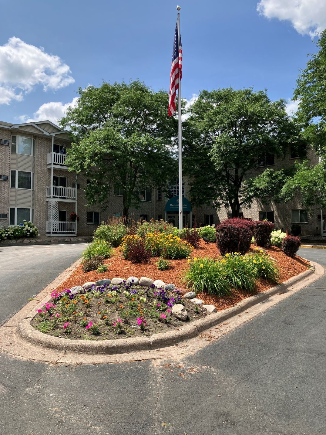 Beautiful landscaped entrance with flowers and American flag