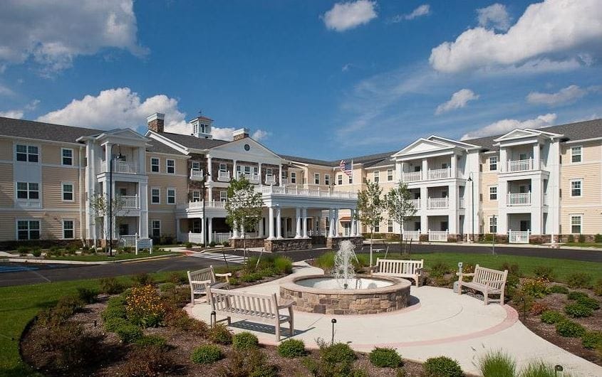 Exterior view of a senior living facility with gardens and benches